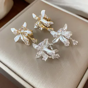 Close-up of elegant flower stud earrings with enamel petals and shiny zirconia