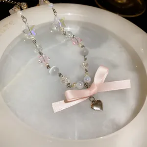 Detailed view of sweet bow necklace featuring heart pendant and luminous cat-eye beads