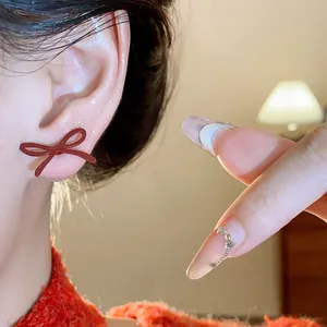 Detailed close-up of a vintage red bow stud earring worn on ear with soft warm lighting