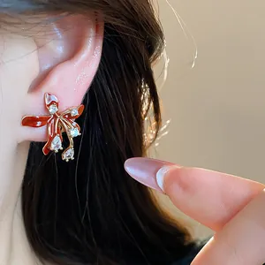 Macro view of a red enamel flower earring with sparkling zircons worn on ear