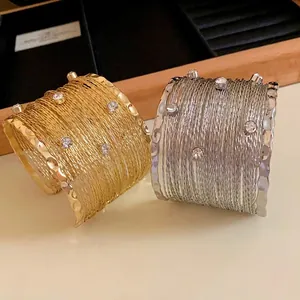 Elegante set di bracciali a polsino multifilo color oro e argento con strass.