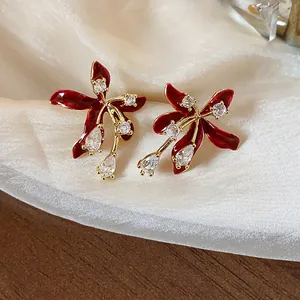 Close-up of elegant red flower stud earrings with gold plating and sparkling zircon