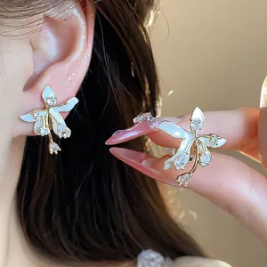 Detail view of 18k gold plated flower stud earrings with zircon and white enamel petals.