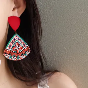 Close-up of vibrant bohemian acrylic earrings with ethnic geometric print on model