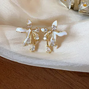 Detail view of 18k gold plated flower stud earrings with white enamel and clear zircon.