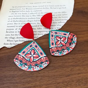 Close-up of retro ethnic printed acrylic drop earrings on a vintage paper background