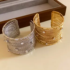 Dettaglio di eleganti bracciali rigidi intrecciati oro e argento con piccoli cristalli