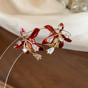 Detailed macro view of elegant red enamel lily earrings with sparkling cubic zircons