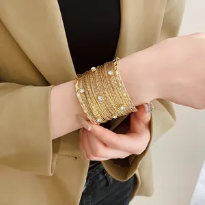 Primo piano di un bracciale rigido dorato multistrato con strass scintillanti sul polso