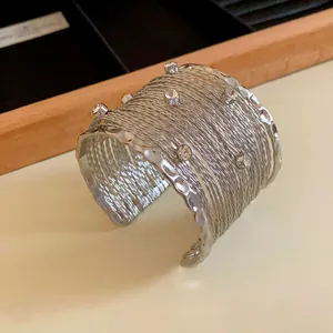 Dettaglio ravvicinato di un bracciale rigido argento a più fili con strass lucidi.