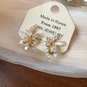 Detail view of flower earrings featuring white enamel petals and shiny zircon crystals