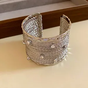 Dettaglio di un bracciale rigido argentato a strati con strass incastonati.