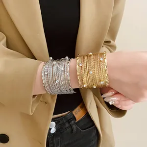 Vista dettagliata di bracciali rigidi multistrato in oro e argento con cristalli lucidi
