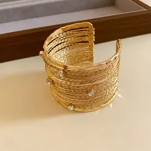 Dettaglio di un bracciale rigido dorato a più strati con cristalli scintillanti