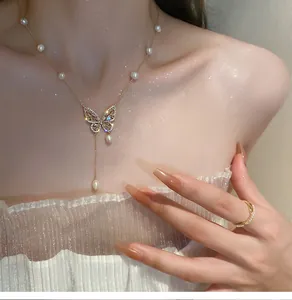 Close-up view of elegant gold butterfly necklace with sparkling pearls and zircons on model