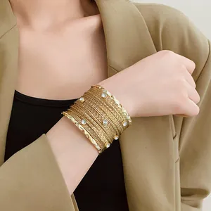 Elegante bracciale rigido dorato multistrato con pietre di zircone scintillanti.