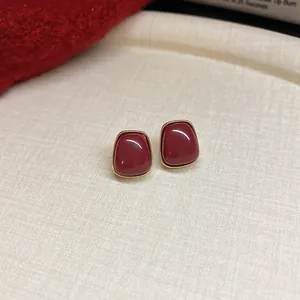 Detailed view of vintage square Anchora red stud earrings with elegant gold metal framing.