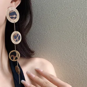 Gros plan sur des boucles d'oreilles léopard avec disques métalliques texturés dorés