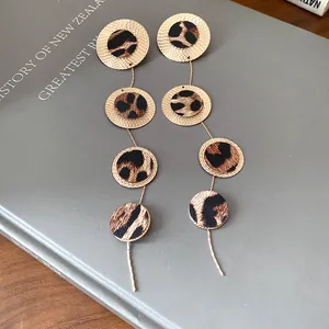 Détail macro de boucles d'oreilles circulaires dorées élégantes avec cuir imprimé léopard