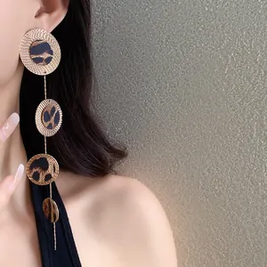 Vue détaillée de longues boucles d'oreilles rondes dorées avec cuir léopard sur mannequin