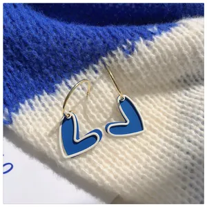 Detailed shot of Klein Blue heart hoop earrings with gold-tone finish on soft knit fabric
