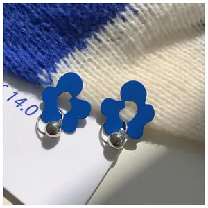 Macro view of minimalist Klein blue flower-shaped earrings with silver bead accents