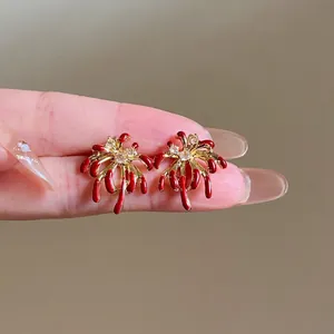 Detail of red enamel firework stud earrings with 18k gold plating and clear zircons