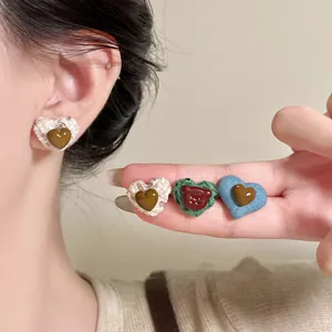 Macro view of stylish heart-shaped fabric and resin stud earrings in multiple colors