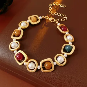 Vintage style bracelet with matte gold frames, pearls, and multi-color stones on leather.