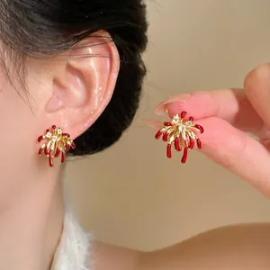 Close-up of 18k gold plated firework stud earrings with red enamel and cubic zirconia