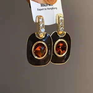 Nahaufnahme von Vintage-Ohrringen in Gold mit schwarzem Emaille und Bernstein