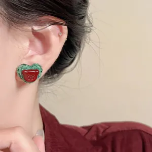 Close-up of heart-shaped fabric stud earring with a cute red resin bear face.