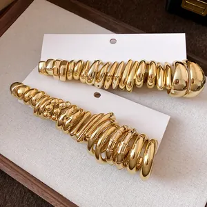 Detail view of minimalist gold-tone C-shaped hoop earring sets on display cards