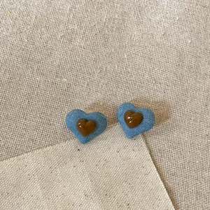 Close-up of heart stud earrings made with blue denim fabric and brown resin center