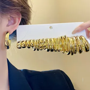 Detailed view of polished gold-tone minimalist C-shaped hoop earring set displayed on card
