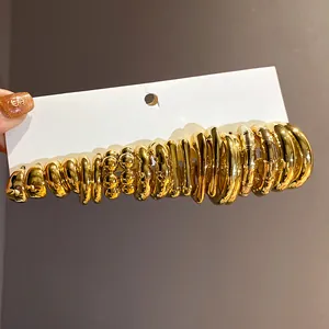 Detailed macro view of polished gold C-shaped hoop earrings on display card