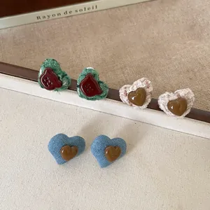Detailed view of heart earrings featuring resin and fabric textures in various colors.