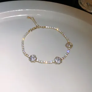 Gros plan d'un bracelet en zircon doré avec motifs fleurs ajourées sur plat blanc