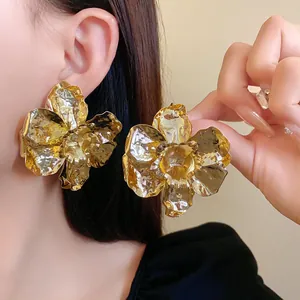 Close-up of elegant gold crumpled metal flower earrings with detailed texture.