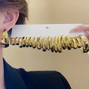 Close-up of a set of chunky gold-tone C-shaped drop earrings with a smooth polished finish