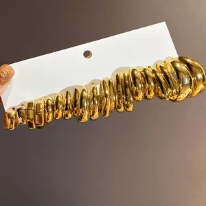 Detailed macro shot of a set of elegant shiny gold C-shaped earrings on a white display card.