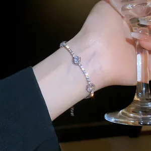 Bracelet fleur argenté étincelant avec zircons au poignet tenant un verre à vin