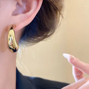 Macro view showing the elegant gold C-shaped glossy stud earring worn on the ear