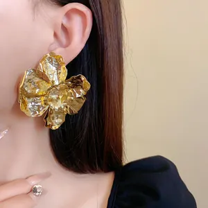 Detailed view of oversized crinkled gold flower earring on model for elegant style