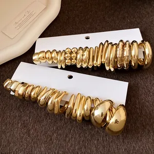 Detail view showing a variety of gold C-shaped earrings arranged on white cards.
