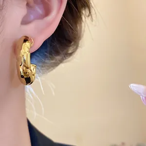Close-up of polished gold C-shaped chunky hoop earring showing reflective texture