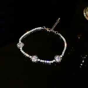 Gros plan d'un bracelet argenté avec zircons étincelants et breloques fleurs sur noir