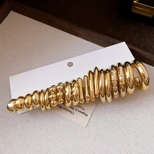 Detail view of various minimalist gold-toned C-shaped hoop earrings set on display