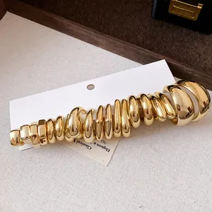 Detailed macro view of various sized gold C-shaped hoop earrings on display card.