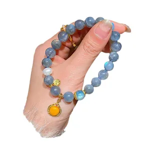 Elegant blue moonstone beaded bracelet with gold charms and orange pendant for women.